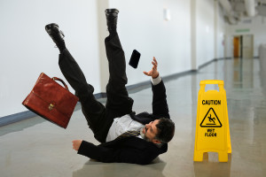 Senior businessman falling near caution sign in hallway